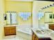 Large bathroom with dual vanities, soaking tub, and block window offers ample space and natural light at 4942 Oldham St, Sarasota, FL 34238