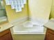 Corner soaking tub with block window and wooden cabinets offers a relaxing spa-like experience at 4942 Oldham St, Sarasota, FL 34238