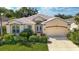 Charming front exterior of a single-story home featuring lush landscaping, an attached two-car garage, and a well-manicured lawn at 4942 Oldham St, Sarasota, FL 34238