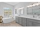 Bright bathroom featuring double vanity, modern fixtures, a soaking tub, and a window with plantation shutters at 5004 Waterkey Way, Tampa, FL 33647