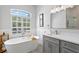 Bright bathroom featuring a soaking tub, modern fixtures, and a window with plantation shutters at 5004 Waterkey Way, Tampa, FL 33647