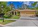 Inviting home featuring a three-car garage, lush landscaping and mature palm trees in the front yard at 5004 Waterkey Way, Tampa, FL 33647
