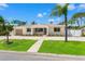 Inviting single-story home with a well-maintained lawn, long driveway, and mature palm trees on a sunny day at 601 Boca Ciega Isle Dr, St Pete Beach, FL 33706