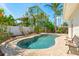 Backyard view featuring a kidney-shaped pool, stone patio, with tropical foliage, bench and adjacent home at 601 Boca Ciega Isle Dr, St Pete Beach, FL 33706