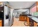 A kitchen with stainless steel refrigerator, wood cabinets, black countertops, and tile flooring overlooking the living room at 7110 N Rome Ave, Tampa, FL 33604