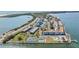 Wide aerial shot showcasing waterfront condo buildings, tennis courts, and a community pool at 9 Forbes Pl # 504, Dunedin, FL 34698