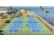 Aerial view of green and blue tennis courts with buildings and bay in the background at 9 Forbes Pl # 504, Dunedin, FL 34698