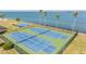 Aerial view of green and blue tennis courts with palm trees and bay at 9 Forbes Pl # 504, Dunedin, FL 34698