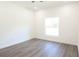 An empty bedroom with grey wood floors, neutral walls, and a bright window offering natural light at 9002 Glenarm Way, Weeki Wachee, FL 34613