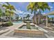 A beautiful pool area surrounded by lush palm trees and a tiki bar under a sunny sky at 1038 Bellasol Way # 202, Apollo Beach, FL 33572