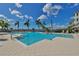 A sparkling swimming pool area with a clear blue sky, framed by swaying palms at 1038 Bellasol Way # 202, Apollo Beach, FL 33572