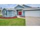 Blue single-story home with red door, lush lawn, landscaping and an attached two-car garage at 12037 Conway St, Spring Hill, FL 34609
