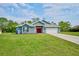 Inviting single-story home featuring a well-manicured lawn, blue siding, and a red front door at 12037 Conway St, Spring Hill, FL 34609