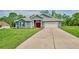 Charming single-story home with long driveway, well-kept lawn, and blue siding under a sunny sky at 12037 Conway St, Spring Hill, FL 34609