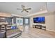 Cozy living room featuring wood flooring, large TV, and glass doors that overlook the private pool at 12037 Conway St, Spring Hill, FL 34609