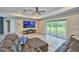 Open living room featuring tray ceilings, a large TV, a sectional sofa, and backyard views at 12037 Conway St, Spring Hill, FL 34609