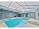 View of the large, screened-in backyard pool with several doors leading into the house at 12037 Conway St, Spring Hill, FL 34609