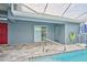 View of the outdoor screened-in pool with a basketball hoop and access doors to the home at 12037 Conway St, Spring Hill, FL 34609