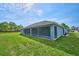 A view of the blue single story house with a green yard and large screened in patio at 12037 Conway St, Spring Hill, FL 34609