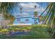 Lush backyard featuring tropical landscaping, seating area, and a charming blue house at 125 11Th Ave, Indian Rocks Beach, FL 33785