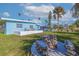 Wide shot of expansive backyard, featuring seating, lush landscaping and vibrant blue house at 125 11Th Ave, Indian Rocks Beach, FL 33785