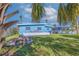 Backyard featuring tropical trees, lush landscaping, seating area, and a charming blue house at 125 11Th Ave, Indian Rocks Beach, FL 33785