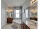 Bathroom view with a soaking tub between two granite countertop vanities and patterned curtains at 12903 49Th E Ln, Parrish, FL 34219