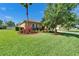 Well-maintained lawn and landscaped front yard with colorful plants and a palm tree on a sunny day at 12903 49Th E Ln, Parrish, FL 34219