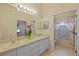 Well-lit bathroom featuring dual sinks, floral wallpaper, and a bathtub with shower at 13750 Dowling Ln, Odessa, FL 33556