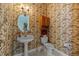 Small powder room with decorative wallpaper and oval mirror at 13750 Dowling Ln, Odessa, FL 33556