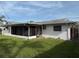 Back view of the home with a screened-in porch, lush green grass, and well-maintained landscaping at 14264 Page Ave, Largo, FL 33774