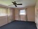Cozy bedroom with plush carpeting, two windows dressed with curtains, and a ceiling fan for added comfort at 14264 Page Ave, Largo, FL 33774