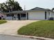 Charming single-story home with a well-manicured front yard and a wide driveway leading to an attached two-car garage at 14264 Page Ave, Largo, FL 33774