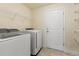 Bright laundry room featuring a front-load washer and dryer, wire shelving, and a convenient storage door at 16302 Vine Cliff Ave, Hudson, FL 34667