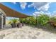 Backyard patio area with shade cover, outdoor seating, and lush tropical landscaping at 16934 Oval Rum Dr, Wimauma, FL 33598