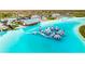 A lively aerial view reveals a lagoon with inflatable water park features in a planned community at 16934 Oval Rum Dr, Wimauma, FL 33598