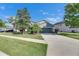 View of this two-story home's driveway, well-kept lawn, mature landscaping and gray exterior at 18734 Burndall Ct, Land O Lakes, FL 34638