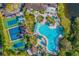 Gorgeous aerial view of a community pool, hot tub, tennis courts, and lush landscaping under a clear blue sky at 1901 Canterbury Ln # 14, Sun City Center, FL 33573