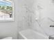 Elegant bathroom featuring marble-style tile in the shower/tub area and a bright window view at 2001 Spooner Dr, Plant City, FL 33563