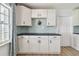Spacious kitchen has white cabinets, black countertops, light blue backsplash, and light wood-look flooring at 2001 Spooner Dr, Plant City, FL 33563