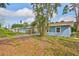 A view of the backyard showing the side of the blue home with a carport and lush vegetation at 3241 Williamsburg St, Sarasota, FL 34231