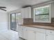 Updated kitchen area featuring white cabinets, mosaic backsplash, and sliding glass doors at 3407 N 48Th St, Tampa, FL 33605
