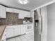 Kitchen area features stainless steel appliances, a mosaic backsplash, and tile flooring at 3407 N 48Th St, Tampa, FL 33605