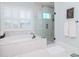Bright bathroom with a soaking tub, glass enclosed shower, and plantation shutters at 511 Erie Ave, Tampa, FL 33606