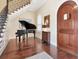 Elegant foyer with a dark wood front door, staircase, and grand piano, complemented by warm lighting at 511 Erie Ave, Tampa, FL 33606