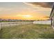 Open backyard with a white fence surrounding a scenic view of a lake at sunset at 8749 Parsons Hill Blvd, Wesley Chapel, FL 33545