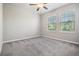 Bright bedroom featuring carpet, ceiling fan, and natural light from the two windows at 8749 Parsons Hill Blvd, Wesley Chapel, FL 33545
