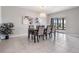 Cozy dining area illuminated by an elegant chandelier, featuring a wooden table and access to outdoor patio at 8749 Parsons Hill Blvd, Wesley Chapel, FL 33545