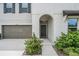 Charming home featuring a gray garage door and a covered arched front entryway, complemented by lush landscaping at 8749 Parsons Hill Blvd, Wesley Chapel, FL 33545