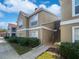Two-story condo building with manicured landscaping, crisp white trim, and a light brown facade under a bright blue sky at 9481 Highland Oak Dr # 703, Tampa, FL 33647